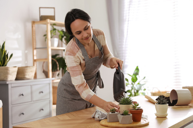 Photo of Mature woman watering houseplants at home. Engaging hobby