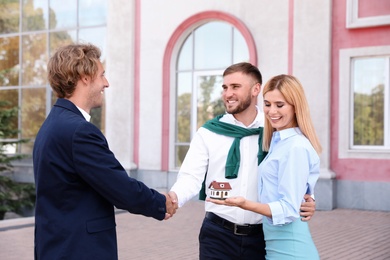 Photo of Male real estate agent shaking hands with clients outdoors