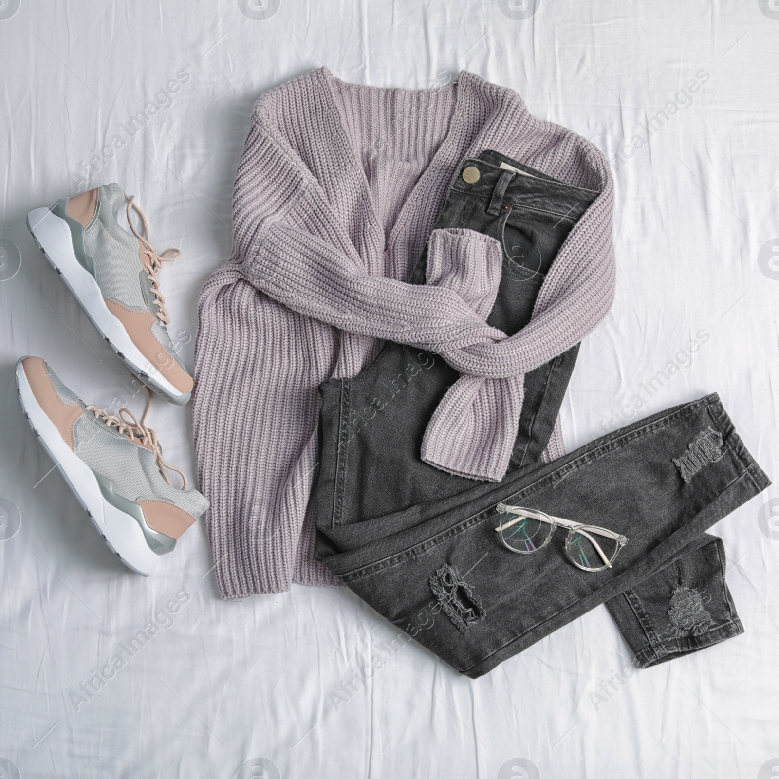 Photo of Flat lay composition with jeans, sweater and shoes on white fabric