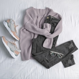 Photo of Flat lay composition with jeans, sweater and shoes on white fabric