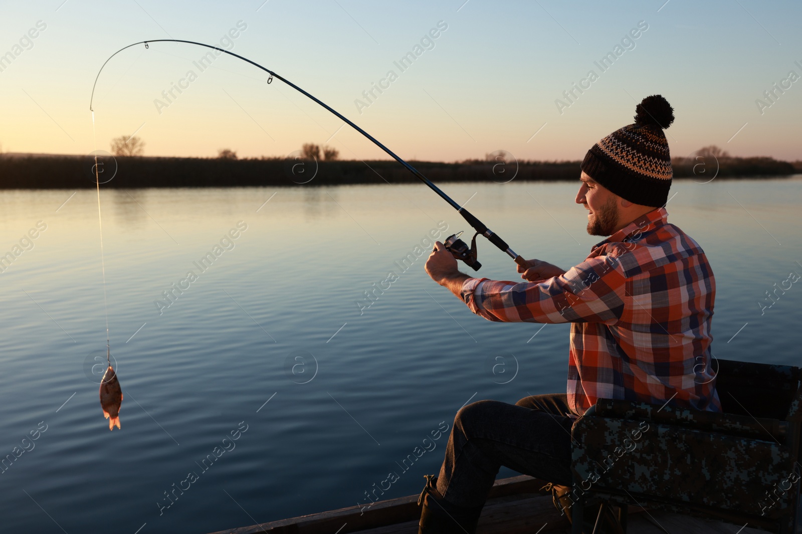 Photo of Fisherman catching fish with rod at riverside