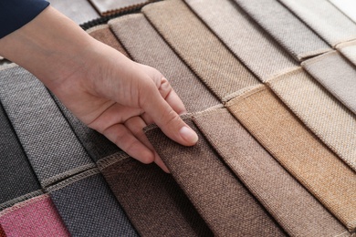 Photo of Young woman choosing among upholstery fabric samples, closeup. Interior design