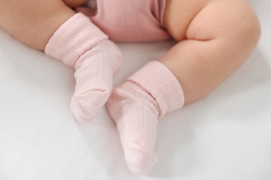 Photo of Little baby in bodysuit on bed, closeup