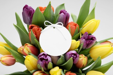 Bouquet of colorful tulips with blank card on white background, closeup