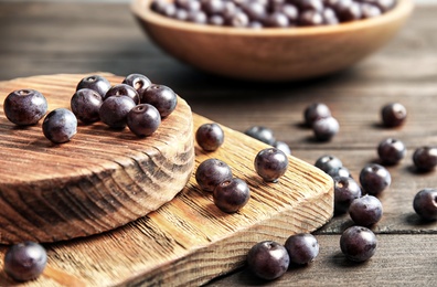 Photo of Fresh acai berries on wooden table, closeup