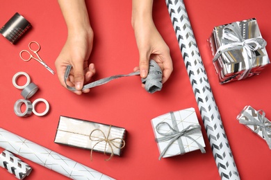 Woman decorating gift box on color background, top view