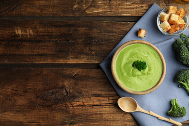 Photo of Delicious broccoli cream soup served on wooden table, flat lay. Space for text