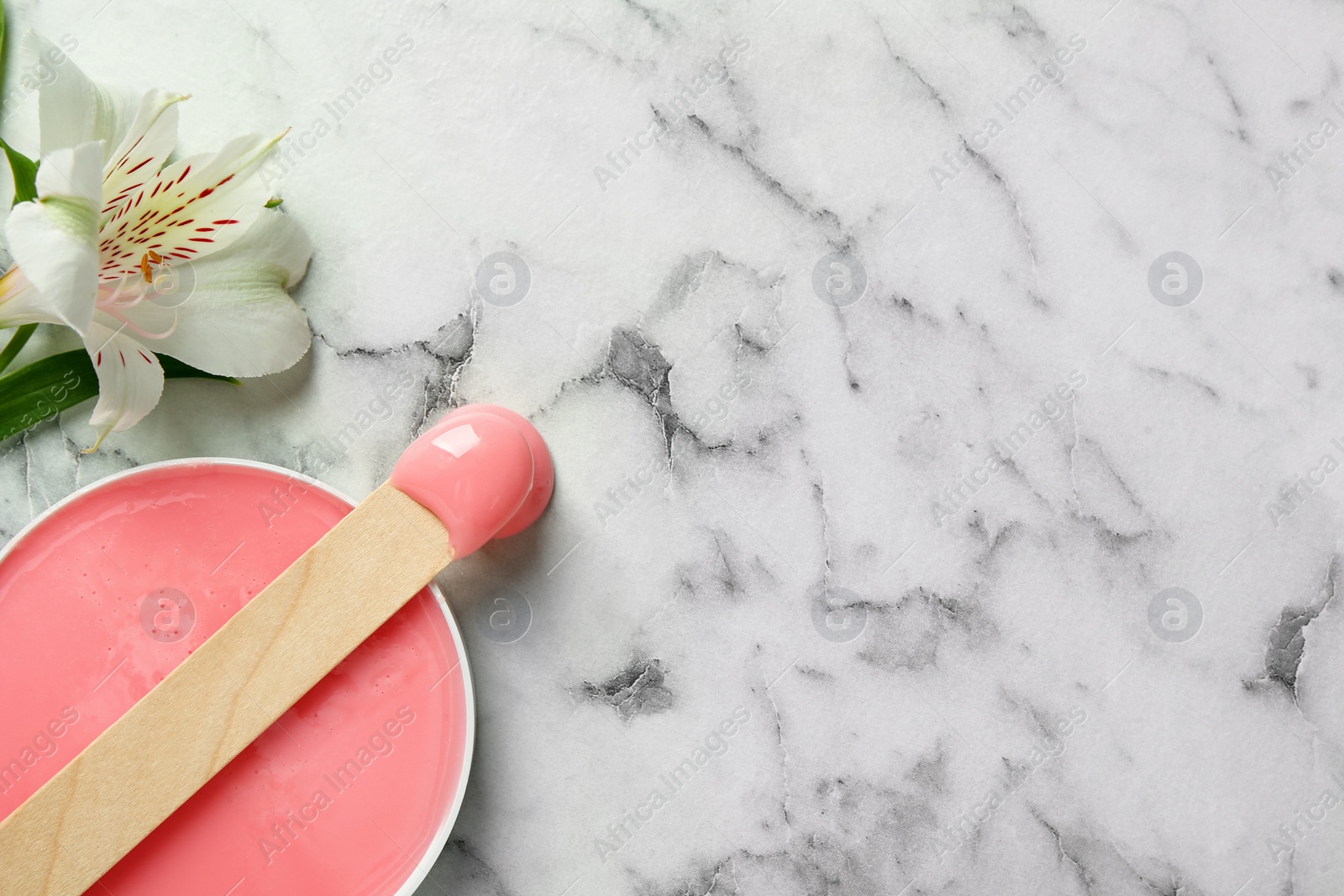 Photo of Spatula with wax and flower on white marble table, flat lay. Space for text