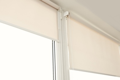 Window with modern roll blinds in room, closeup