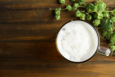 Photo of Flat lay composition with tasty beer, fresh green hops and space for text on wooden background