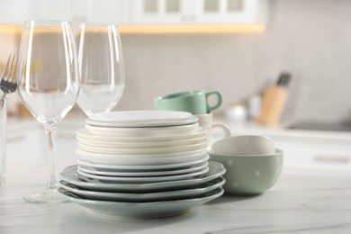 Photo of Many different clean dishware and glasses on white marble table in kitchen