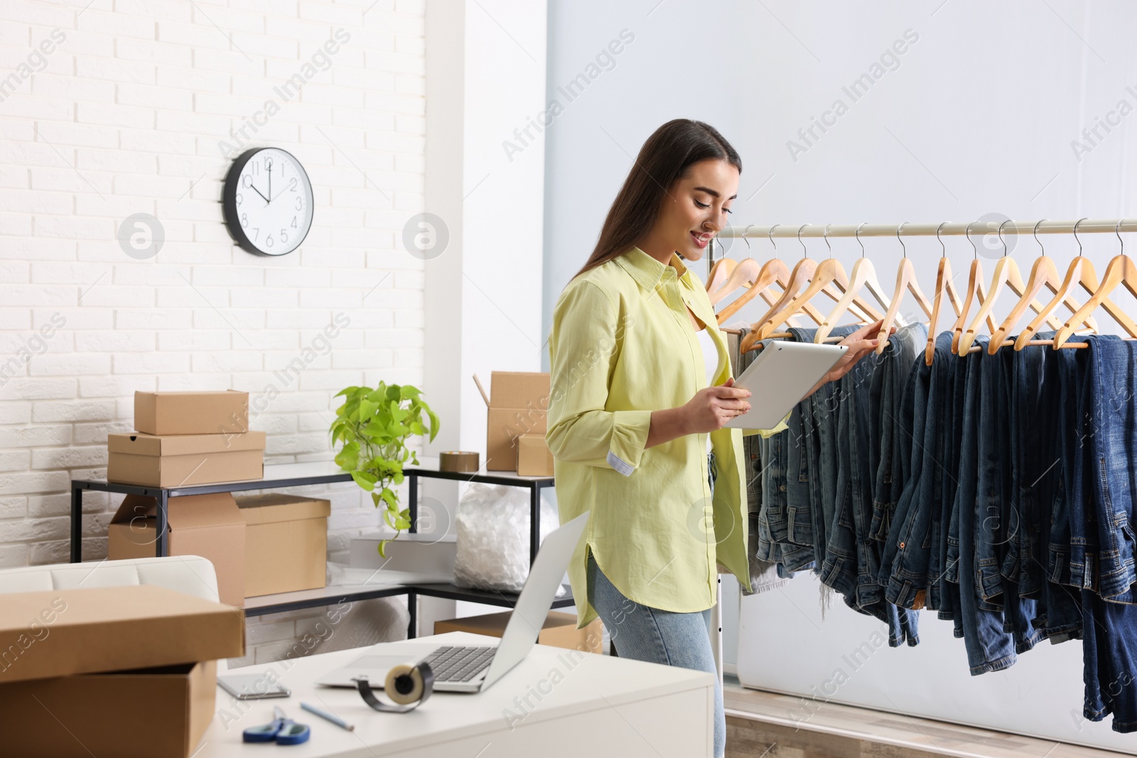 Photo of Clothes seller working with tablet in office. Online store