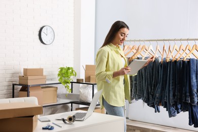 Photo of Clothes seller working with tablet in office. Online store