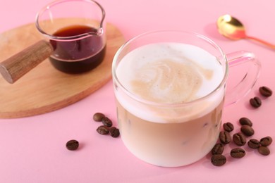 Cup of fresh coffee and beans on pink table, closeup