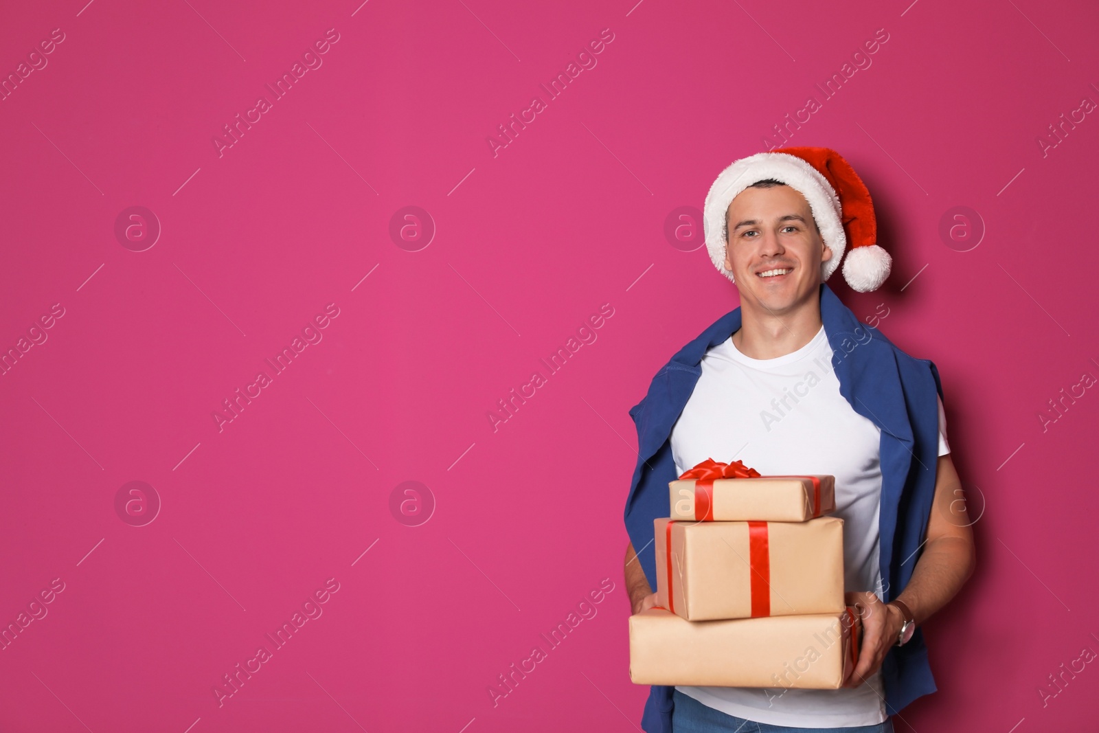 Photo of Young man with Christmas gifts on color background