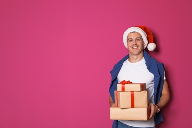 Young man with Christmas gifts on color background