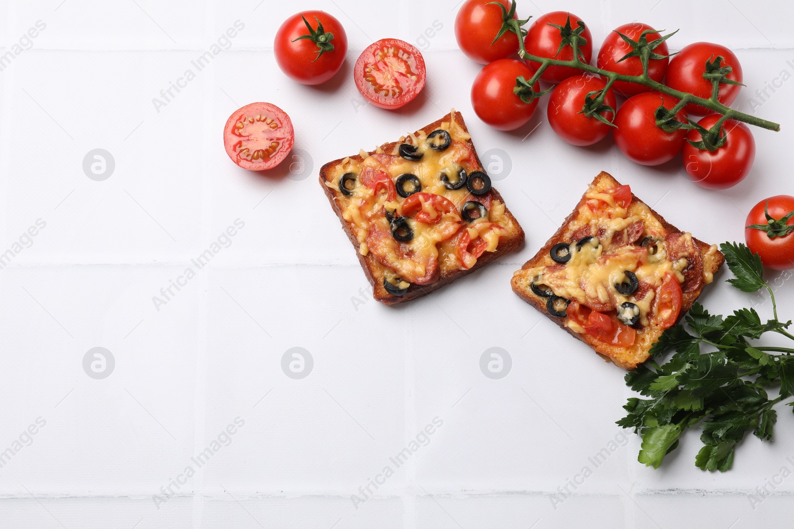 Photo of Tasty pizza toasts, fresh tomatoes and parsley on white tiled table, flat lay. Space for text