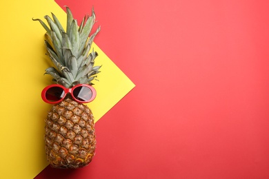 Photo of Top view of pineapple with sunglasses on color background, space for text. Creative concept