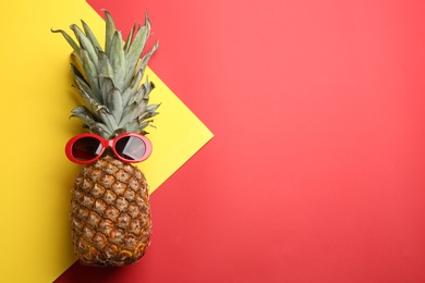 Top view of pineapple with sunglasses on color background, space for text. Creative concept