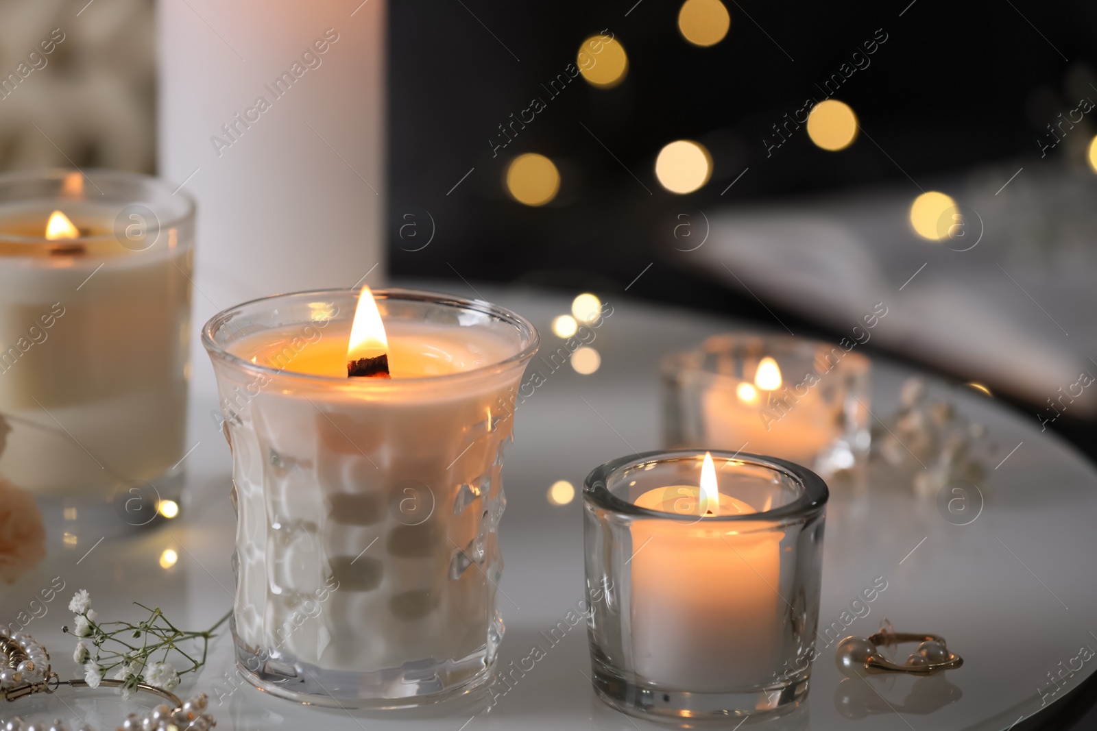 Photo of Burning candles and jewelry on table indoors