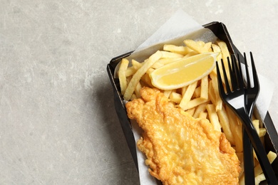 Photo of Disposable container with British Traditional Fish and potato chips on grey background, top view. Space for text