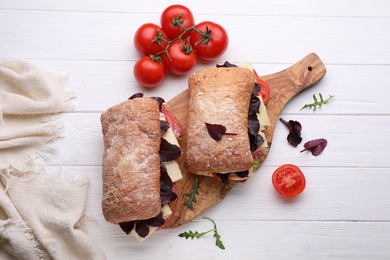 Photo of Delicious sandwiches with cheese, salami, tomato on white wooden table, flat lay