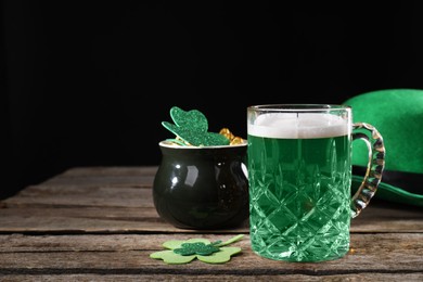 Photo of St. Patrick's day party. Green beer, leprechaun hat, pot of gold and decorative clover leaves on wooden table. Space for text