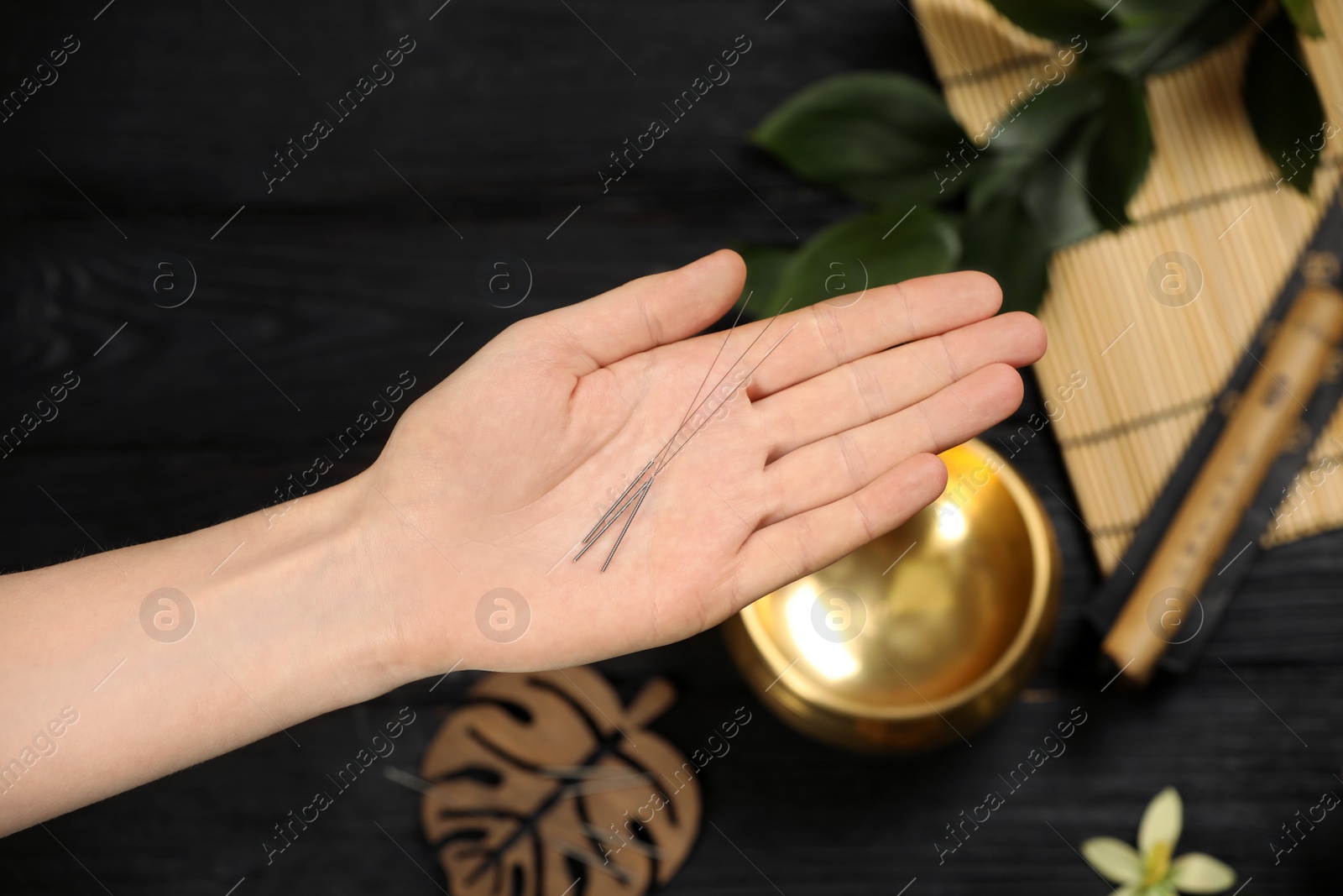 Photo of Woman holding many acupuncture needles over table, top view