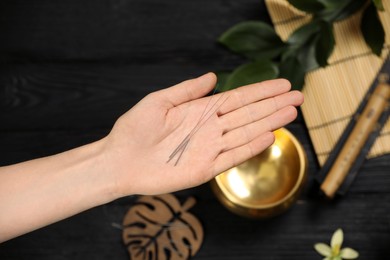 Photo of Woman holding many acupuncture needles over table, top view