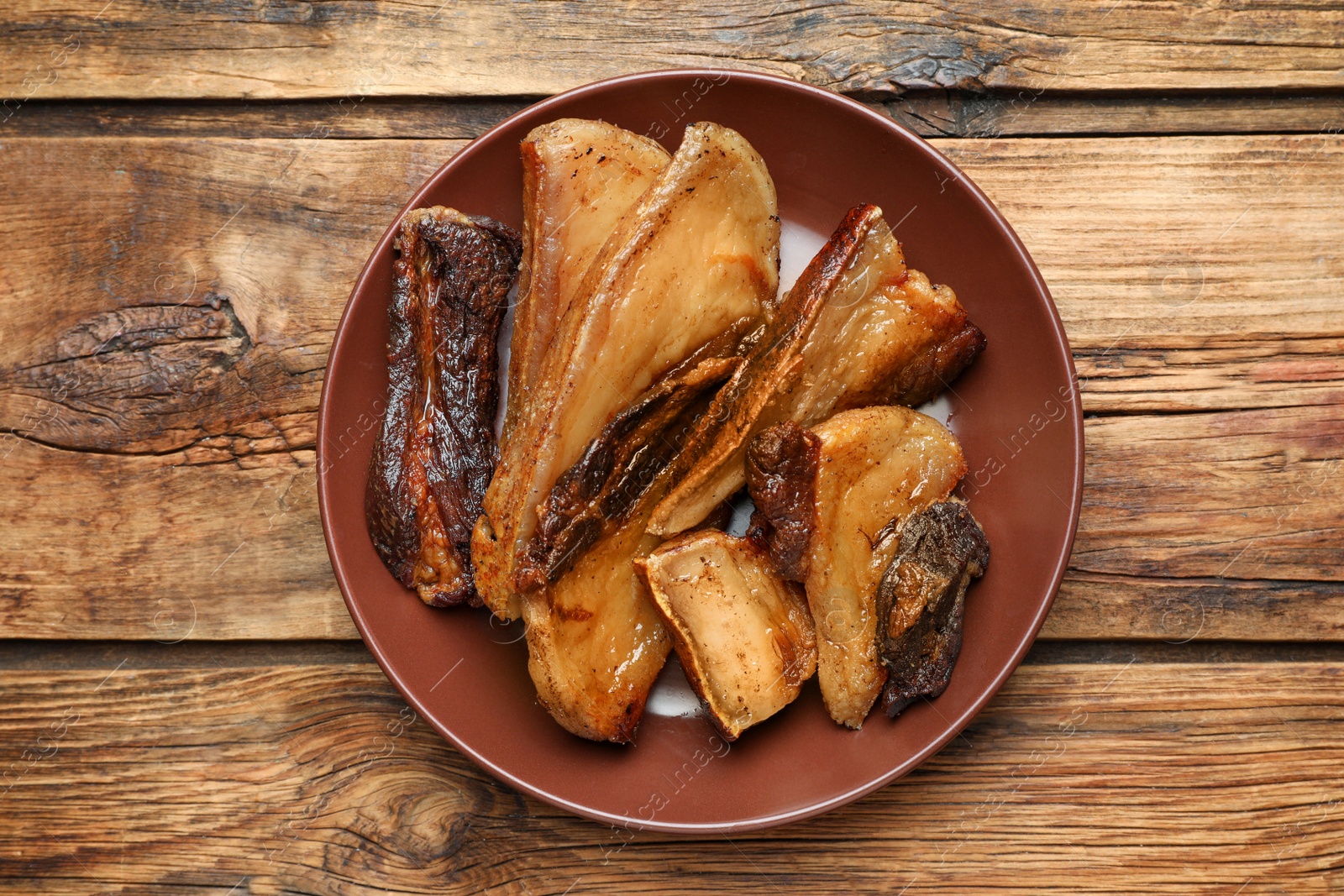 Photo of Tasty fried cracklings on wooden table, top view. Cooked pork lard