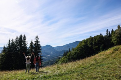 Women enjoying mountain landscape on sunny day, back view. Space for text