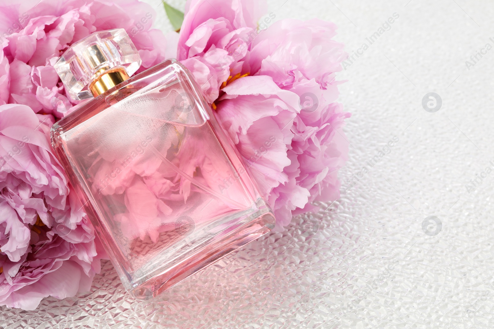 Photo of Luxury perfume and floral decor on white plastic surface, space for text