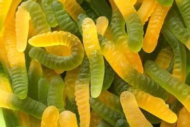 Photo of Sweet color jelly worms as background, top view