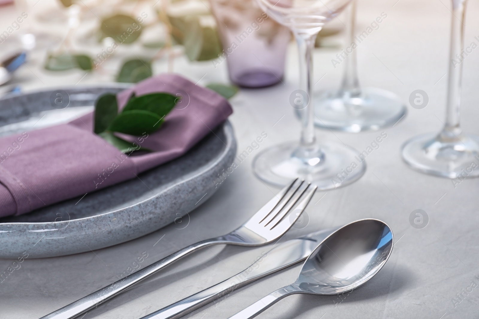 Photo of Cutlery, plate and napkin on light background, closeup. Festive table setting