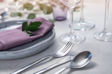 Photo of Cutlery, plate and napkin on light background, closeup. Festive table setting