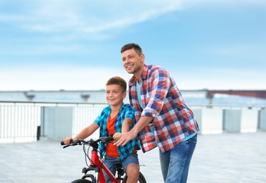 Photo of Dad teaching son to ride bicycle outdoors