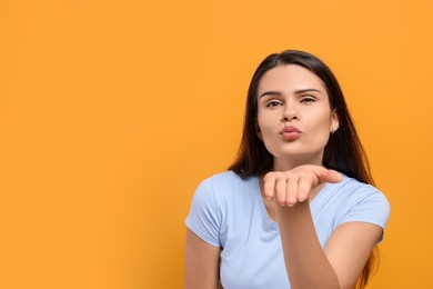 Photo of Beautiful young woman blowing kiss on yellow background. Space for text