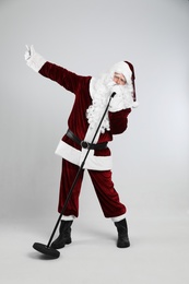 Santa Claus singing with microphone on light grey background. Christmas music