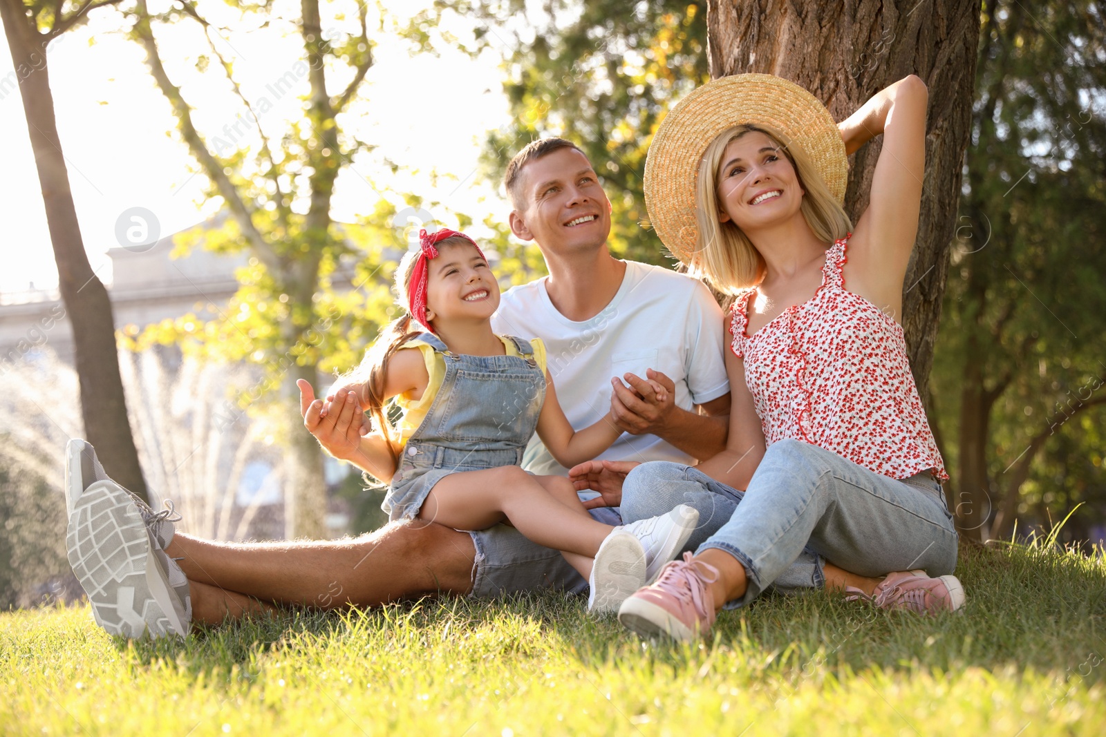 Photo of Happy parents with their child having fun on green grass. Spending time in nature