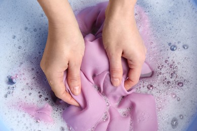Top view of woman hand washing color clothing in suds, closeup