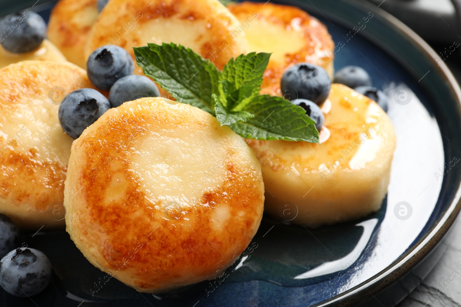 Photo of Delicious cottage cheese pancakes with blueberries on plate, closeup