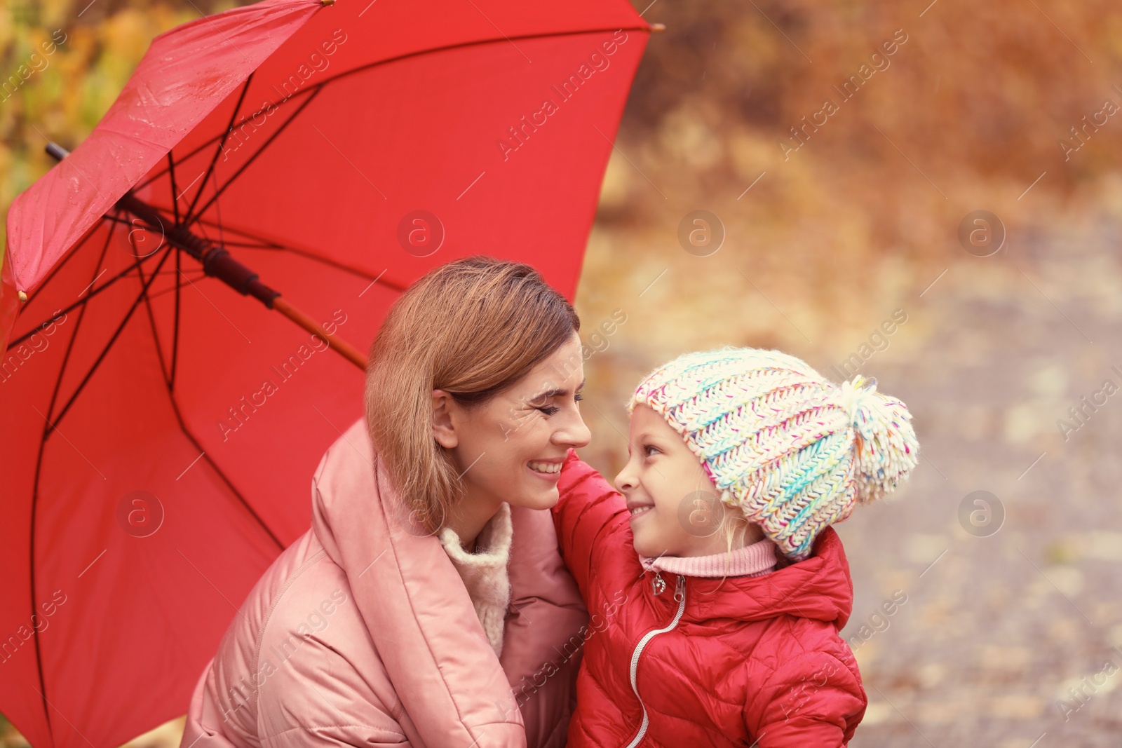 Photo of Mother and daughter with umbrella in autumn park on rainy day