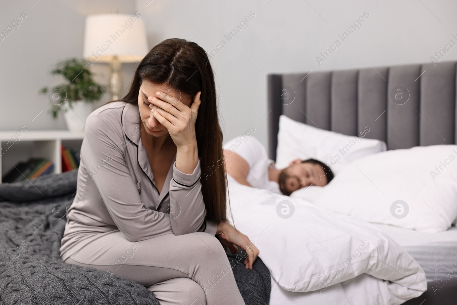 Photo of Stressed wife after quarrel with her husband sitting on bed, selective focus. Relationship problems