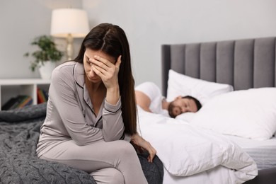 Stressed wife after quarrel with her husband sitting on bed, selective focus. Relationship problems