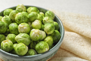 Photo of Bowl of fresh Brussels sprouts and napkin on table, closeup. Space for text