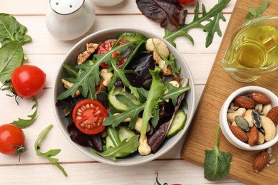 Tasty fresh vegetarian salad and ingredients on light wooden table, flat lay