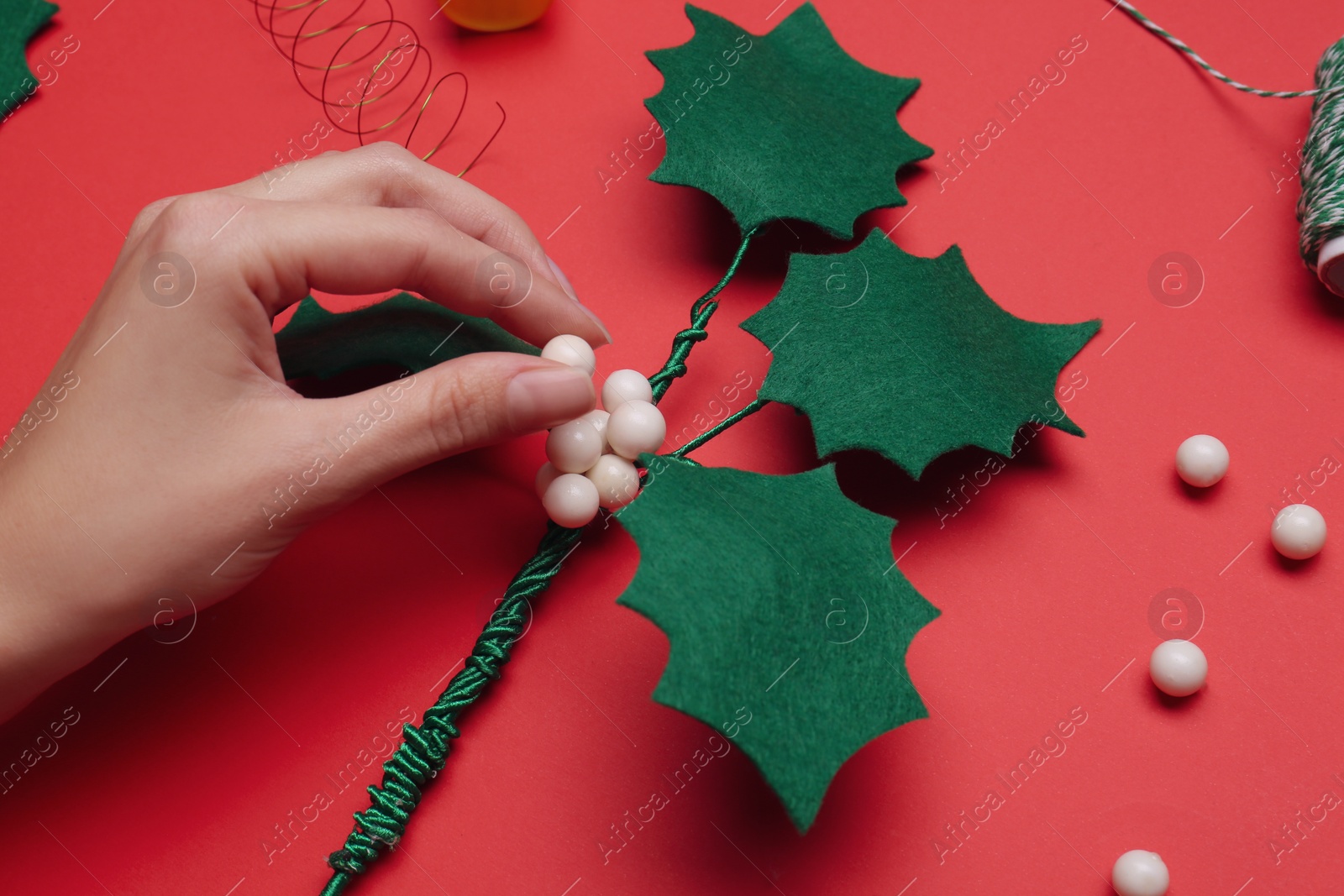 Photo of Woman making mistletoe branch on red background, top view