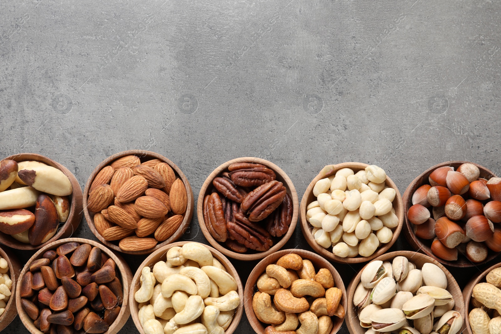 Photo of Flat lay composition with organic nuts and space for text on grey background, top view. Snack mix