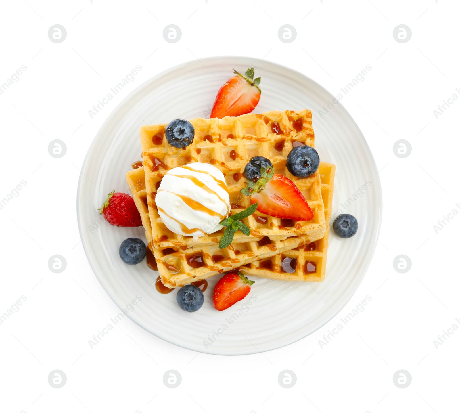 Photo of Tasty Belgian waffles with ice cream, berries and caramel syrup on white background, top view