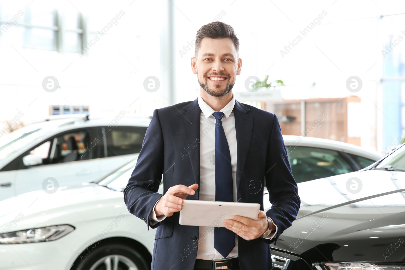 Photo of Salesman with tablet in salon. Buying new car